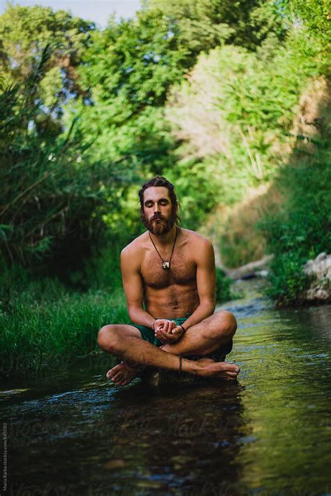 Bearded Naked Male Sitting Down On The River With Eyes Closed Del Colaborador De Stocksy