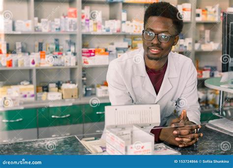 Experienced African American Man Pharmacist In White Coat Working In
