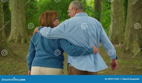 Couple Of Old Mature People Walking In The Park Togetherman Gently Hugging A Woman View From