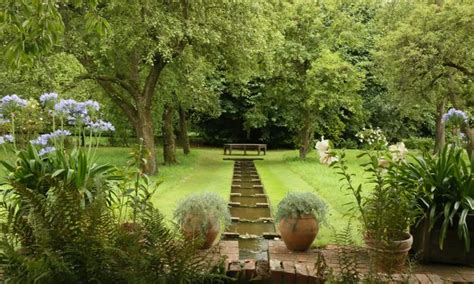 an outdoor garden with steps leading up to a bench in the center and flowers on the other side