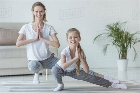Mother And Daughter Practicing Yoga Together At Home Stock Photo
