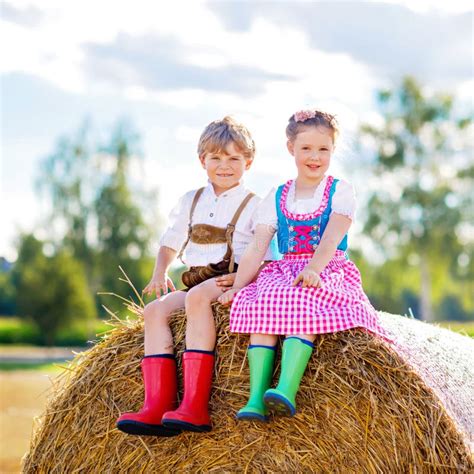 Two Kids In Traditional Bavarian Costumes And Red And Green Rubber