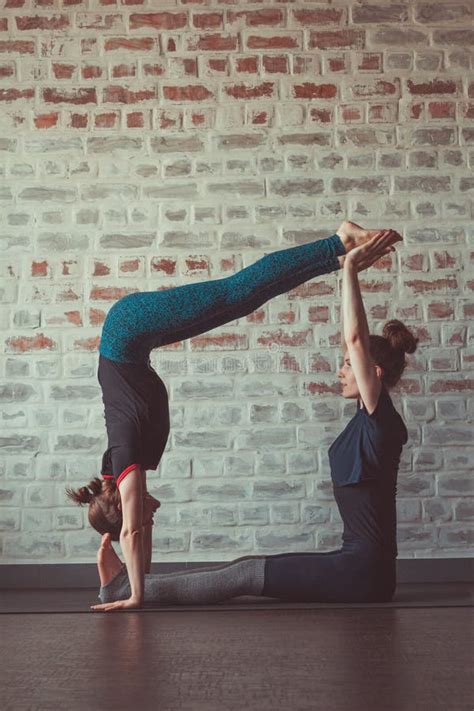 Two Beautiful Women Doing Partner Yoga In Yoga Studio Opposite Brick Wall Stock Photo Image Of