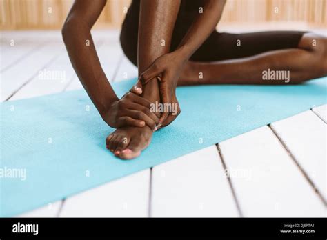 Unrecognizable Barefoot Dark Skin Multiracial Woman Touching Feet Stretch And Do Yoga Stiff