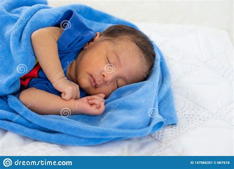 Close Up View Of Asian Young Newborn Baby Is Sleeping With Blue Towel