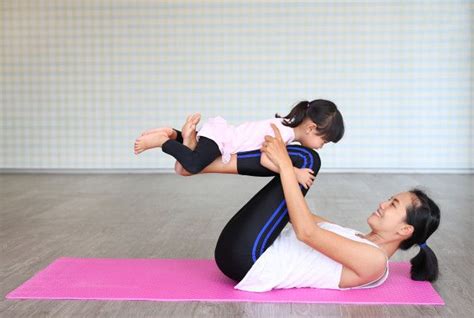A Woman Holding A Baby On Her Back While Doing Yoga Exercises For The