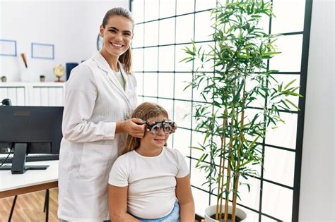 woman and girl oculist and patient examining vision using optometrist glasses at clinic stock