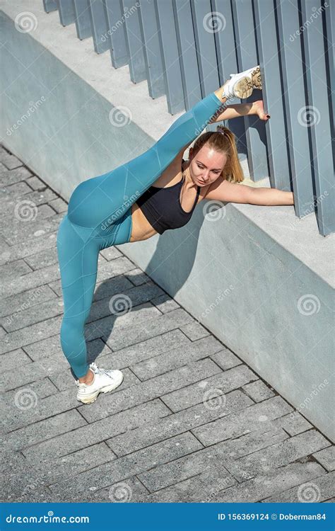 Beautiful Athletic Young Girl In Sportswear Doing Exercises For Stretching On The Street The