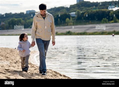 Padre E Hijo Caminando Juntos Tomando Las Manos Por El Río Fotografía
