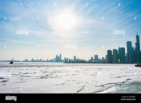 A Buoy In A Frozen Lake Michigan In Chicago With The Sun And Skyline