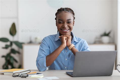 Black Female Secretary Sitting At Workplace In Modern Office Smiling