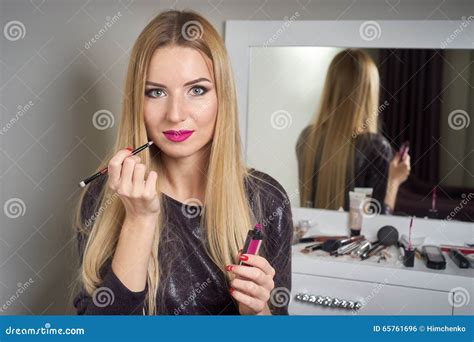 Reflection Of Young Beautiful Woman Applying Her Make Up Looking In A