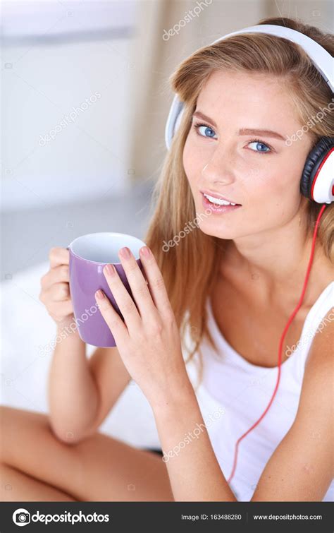 portrait of beautiful woman in morning listening music sitting on bed at home portrait of