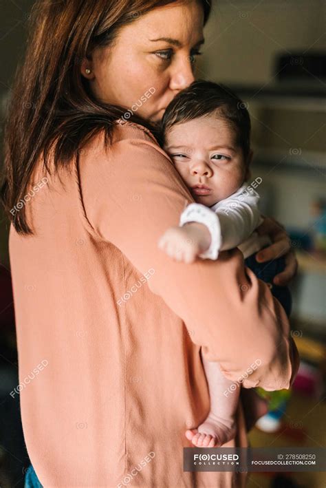 Volver Ver Morena Mamá Abrazando Lindo Bebé Mirando Hacia Fuera En Casa