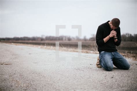 Man Kneeling In Prayer In The Middle Of A Road Kneeling In Prayer