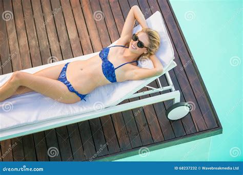 Beautiful Woman In Blue Bikini Lying On Sun Lounger By Poolside On A
