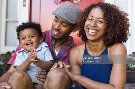 Laughing Mixed Race Couple Sitting On Front Stoop With Son High Res