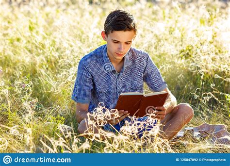 Young Man Sitting In Nature Reading A Book Stock Photo Image Of Field
