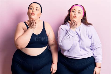 Young Plus Size Twins Wearing Sportswear Looking At The Camera Blowing