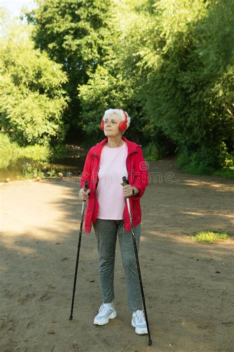 Sporty Senior Woman Trains Endurance While Nordic Walking In Nature