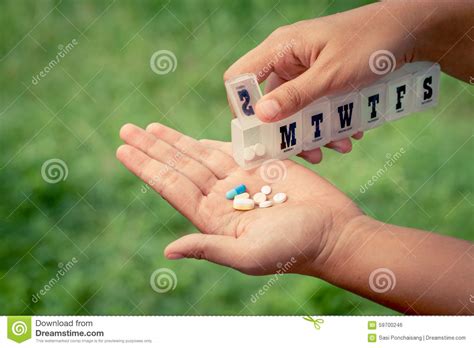 Woman Hand Pouring Pills From A Pill Reminder Box Into Her Hand Stock
