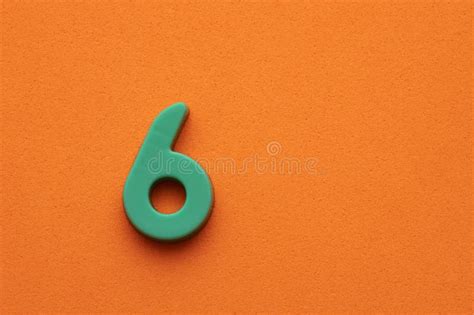 Green Plastic Number Six Plastic Digit On Orange Foamy Background