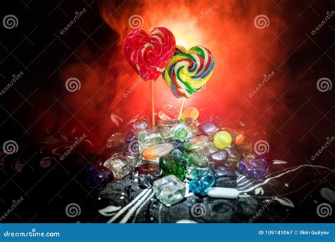 Few Colorful Candy Heart Lollipops On Different Colored Candies Against