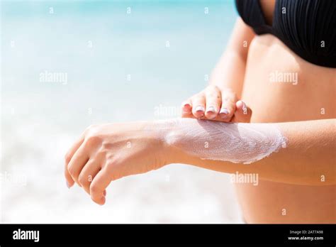 Pretty Girl Is Putting Sun Lotion On Her Hand At The Beach Stock Photo