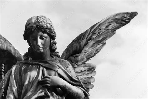 Sad Angel Sculpture With Open Long Wings Across The Frame Against A