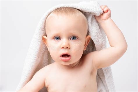 A Young Boy Is Holding A White Towel On His Head With One Hand Baby