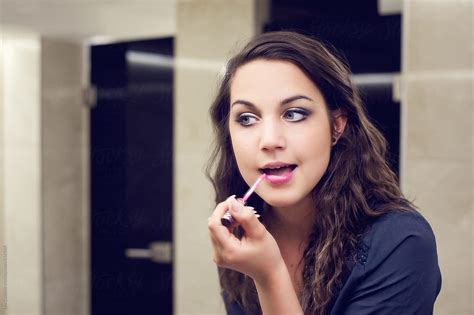 Girl Looking Herself In A Bathroom Mirror Fixing Her Makeup And Putting Lipstick On By
