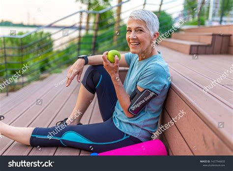 Sporty Woman Eating Apple Beautiful Woman With Gray Hair In The Early