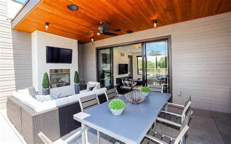 Wooden chairs with slatted backs, a table, and green cushions on an outdoor deck. 33 Stunning Modern Patio Ideas (Pictures) - Designing Idea