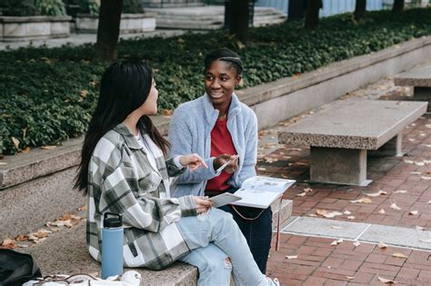 Happy Black Woman Talking To Unrecognizable Girlfriend On City Bench