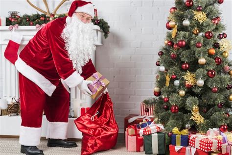 Free Photo Santa Putting Gifts Under Christmas Tree