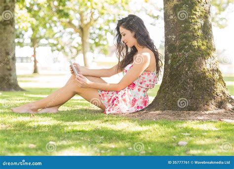 Stylish Attractive Brunette Sitting Under A Tree Using Tablet Stock