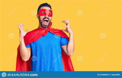 Young Hispanic Man Wearing Super Hero Costume Crazy And Mad Shouting