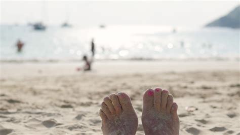 Close Up Of Sandy Feet Wiggling Toes On Tropical Beach Vacation Stock