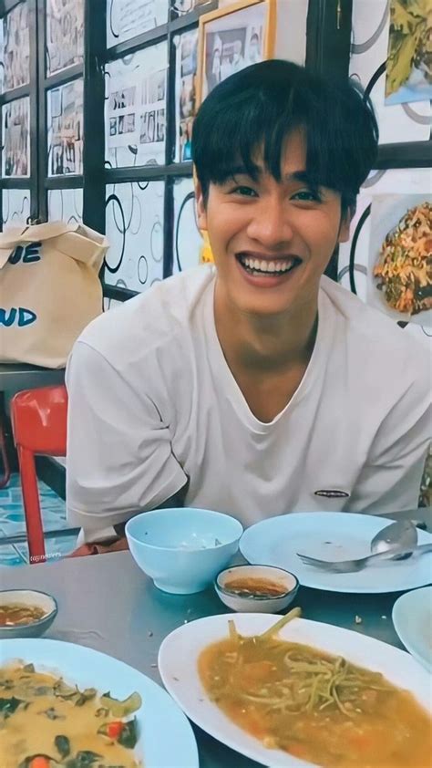 a man sitting at a table filled with bowls of food and smiling for the camera