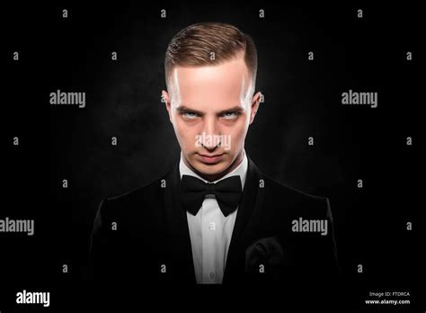 Elegant Young Man In Suit Looking Frowning On Dark Background Stock