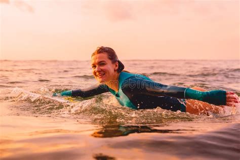 Donna Attraente Del Surfista Su Una Nuotata Del Surf In Oceano Praticando Il Surfing Al Tramonto