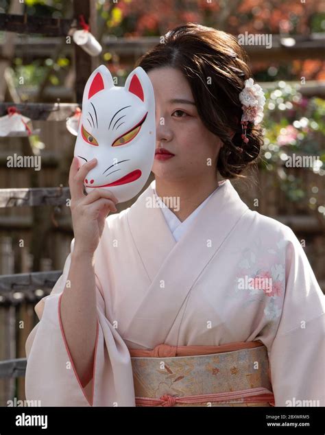 Japanese Teen Wearing Traditional Kimono Is Posing With A Kitsune Mask
