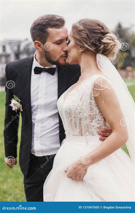 Gorgeous Bride And Stylish Groom Gently Hugging And Kissing Outdoors