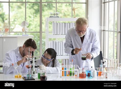 Scientist With Colleagues Using Microscope At Laboratory Stock Photo