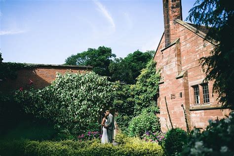 A Bride And Groom Standing In Front Of An Old Brick Building Surrounded