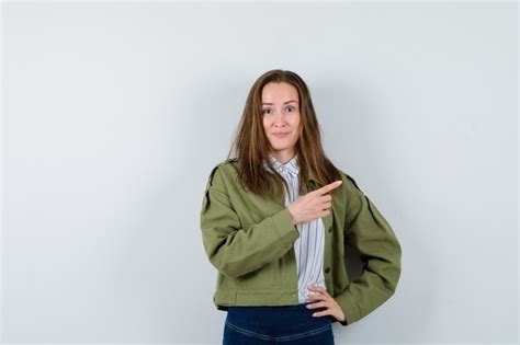 Free Photo Young Lady Pointing Aside In Shirt Jacket And Looking Cheery Front View