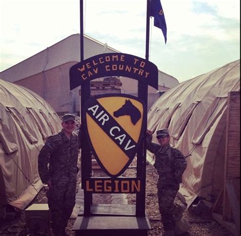 Two Soldiers Standing In Front Of A Sign That Reads Air Cavalry Legon