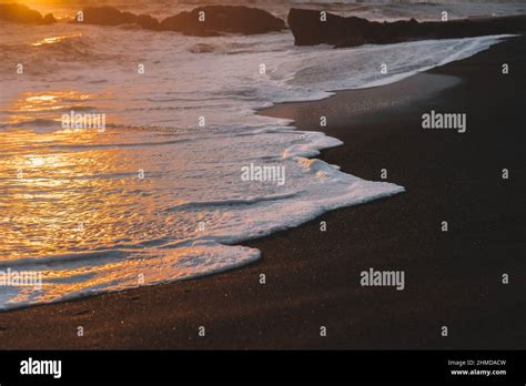 Closeup Of Ocean Waves Foaming On The Beach During Sunset Black Sand
