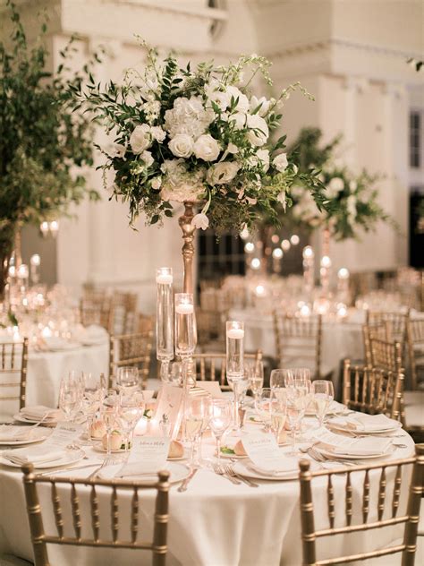 An Elegant Wedding Reception With Tall Centerpieces And White Flowers