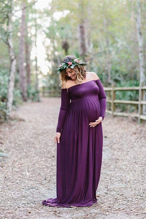 A Pregnant Woman Wearing A Purple Dress Standing In The Woods With Her